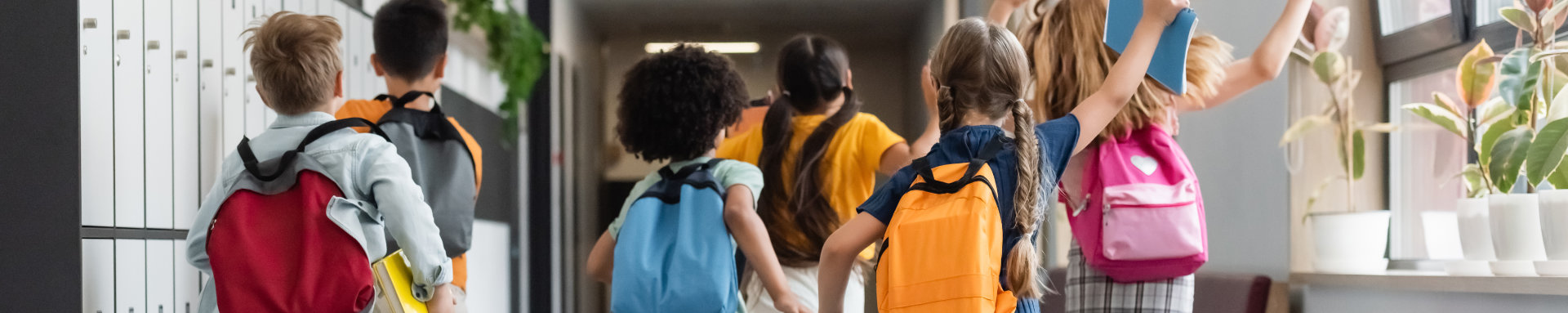 Zes rennende kinderen met rugzak op, gezien van achteren